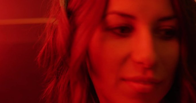 Young woman in photography dark room - red light - creative retro - looks over her images