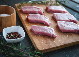Raw pork chops on cutting board with seasonings