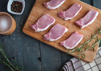 Raw pork chops on cutting board with seasonings, top view