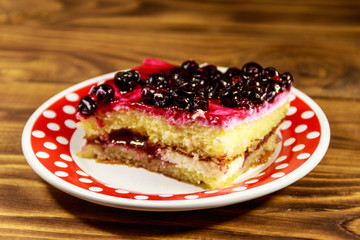 Tasty cheesecake with black currant on wooden table