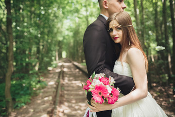 Happy wedding couple charming groom and perfect bride posing in park