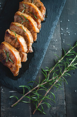 Roasted pork chops with fresh rosemary on dark background, top view