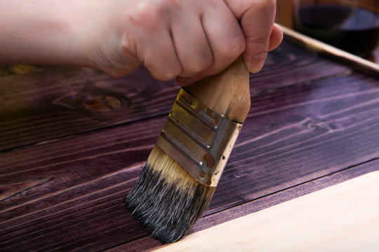 Tinting in the dark color of wood with a brush. Painting boards and protection of wood