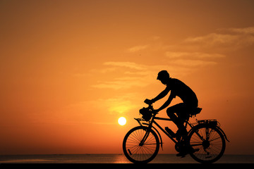 Silhouette man and bike relaxing on sunrise