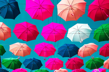 Fototapeta na wymiar Multicolored floating umbrellas against the blue sky.