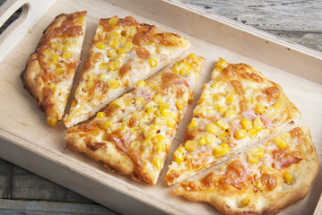 Colorful sliced homemade pizza for kids with cheese and sweet corn. Italian traditional food. Top view.