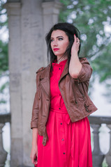Fototapeta premium Portrait of attractive happy woman in red dress and brown leather jacket