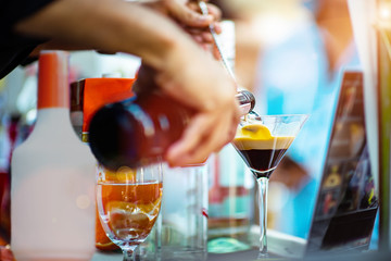 bottle of fruit cocktail pour into a cocktail glass by bartender for mixing make cocktail party...