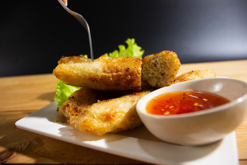 Fried spring rolls stab on fork with chili sauce.