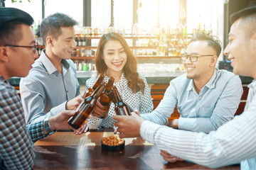 Group of cheerful coworkers drinking beer in pub after work
