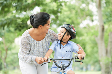 Obraz premium Mother helping her little son cycling in park