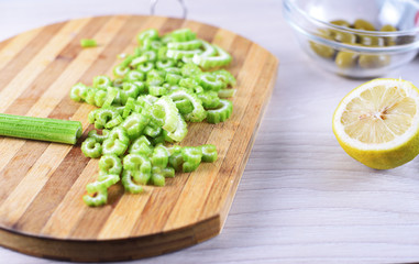 Sliced celery on cutting board with lemon and olive
