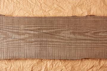 top view of wooden plank on crumpled paper backdrop