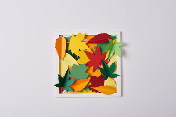 flat lay with handcrafted paper leaves and frame on white tabletop