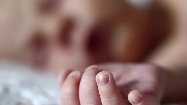 Newborn baby sleeps. Full-term newborn 2 weeks old baby boy lies on the bed and sleeps. Little baby hand in the foreground
