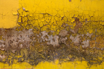 concrete wall with a textured, crumbling, yellow plaster