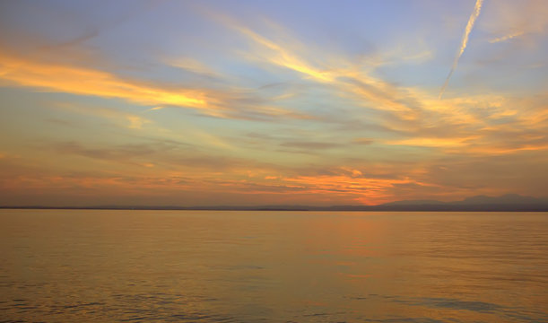 Beautiful sunset. Blurred shot of the dramatic sunset on the lake. Dramatic clouds as a defocused natural background.