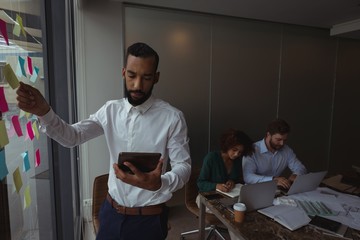 Architect using tablet while colleagues working in background
