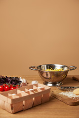 spaghetti in metal colander surrounded with ingredients for pasta on wooden table