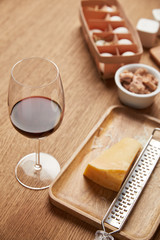 close-up shot of grated cheese and glass of red wine on wooden table