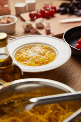 close-up shot of plate on spaghetti surrounded with ingredients on wooden table