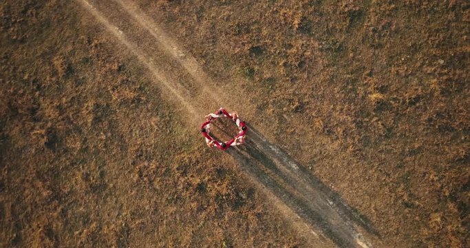 Aerial view: Top down view. A team of dancers circling in dance in the glade