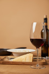 glass and bottle of red wine and grated parmesan for pasta on wooden table