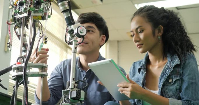 Asian young electronics engineer building, fixing robotics in laboratory. People with technology or innovation concept.