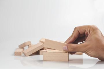 Hand Holding wooden blocks outstanding among the collapse of fall in line.