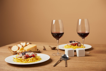 plates of delicious pasta with red wine in glasses on wooden table