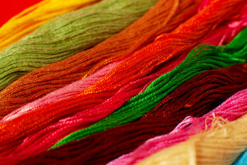 Many threads for embroidery. Macro. Multicolored threads for embroidery are folded in a row. Embroidery is a kind of needlework. Red, blue, green, yellow, orange thread.