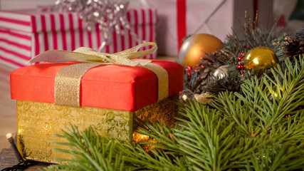 Fototapeta na wymiar Closeup image of golden gift box with ribbon bow with Christmas decorations on wooden floor