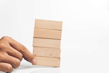 Hand holding wooden blocks on the stack of wooden blocks