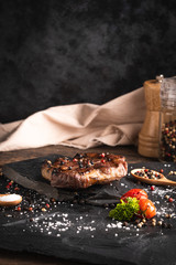 Grilled pork steak, asparagus, salt and pepper on black stone plate