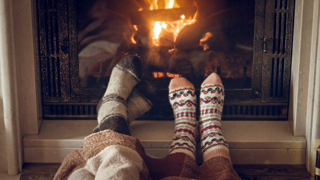 Toned closeup image of family wearing warm knitted socks lying by the fireplace at house