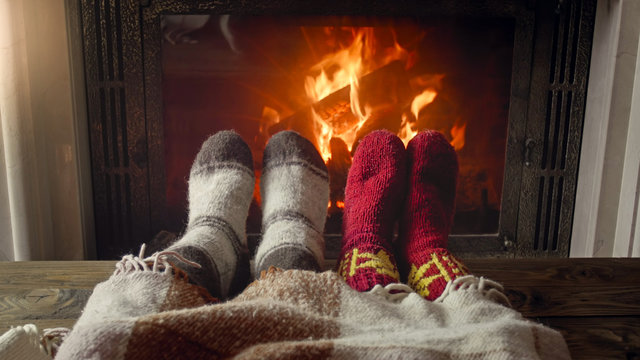 Closeup Photo Of Family Lying Under Blanket Next To Burning Fireplace At Night