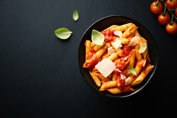 Tasty tomato pasta in bowl on dark