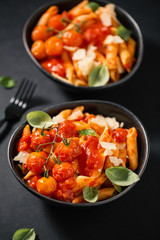 Tasty tomato pasta in bowl on dark