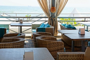 part of the terrace of the restaurant with tables and chairs on the background of the sea