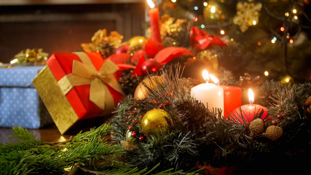 Closeup image of burning candles in Christmas wreath at living room