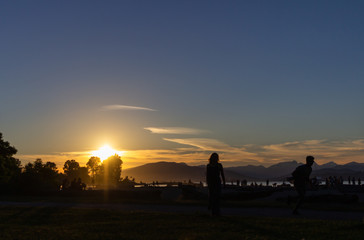 Fototapeta na wymiar Person enjoying sunset, Kitsilano Beach Park, Vancouver, BC, Canada.