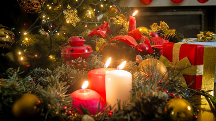 Fototapeta na wymiar Closeup image of three burning candles against glowing colorful Christmas lights