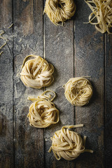 Variety of italian homemade raw uncooked pasta spaghetti and tagliatelle with semolina flour over...
