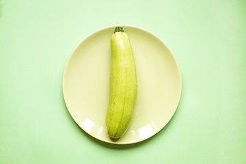 Fresh zucchini on green paper background.Top view