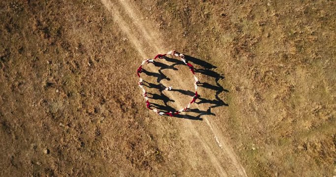 Aerial view: Top down view. A team of dancers circling in dance in the glade