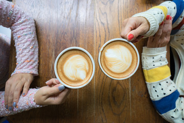 Couple woman hands holding cup of coffee on wooden table