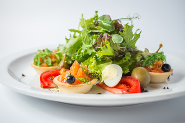 Fresh salad with salmon, olives, green, tomatoes and quail eggs