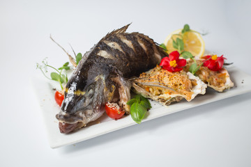 Backed dorada with salsa in shell, green, tomatoes, red flowers and lemon