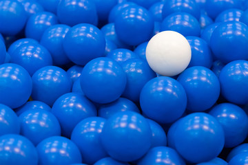 white plastic ball on blue plastic balls, concept : different, out standing
