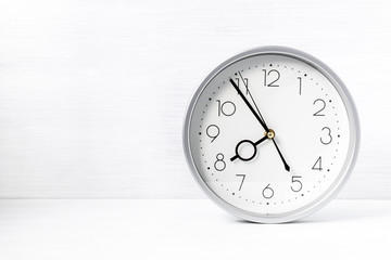 Silver wall clock on white wooden desk